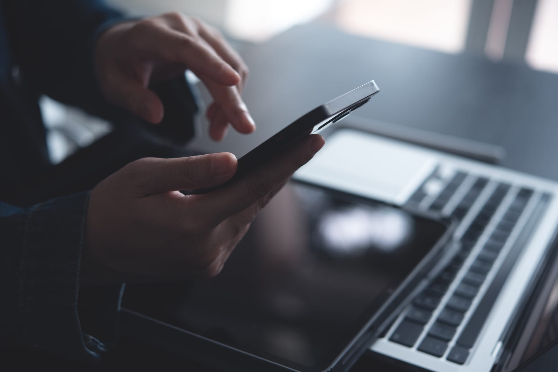Dizüstü bilgisayarın başında telefon kullanan biri